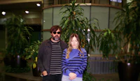 a man and a woman standing in front of plants